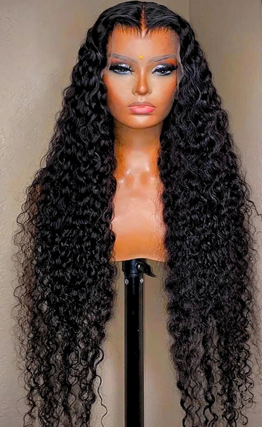 The model is showcasing our Lulama wig which is a long Water wave Brazilian Frontal wig, with a 13x4 or 13x6 ear to ear transparent swiss lace. The wig is Premium quality - 100% raw virgin human hair with cuticles intact and aligned. It is a glue-less wig with adjustable and detachable bands. It has a pre-plucked hairline and can be customised to a ready and go wig by adding bleached knots. Comes in a length of 24” and forms part of our affordable range